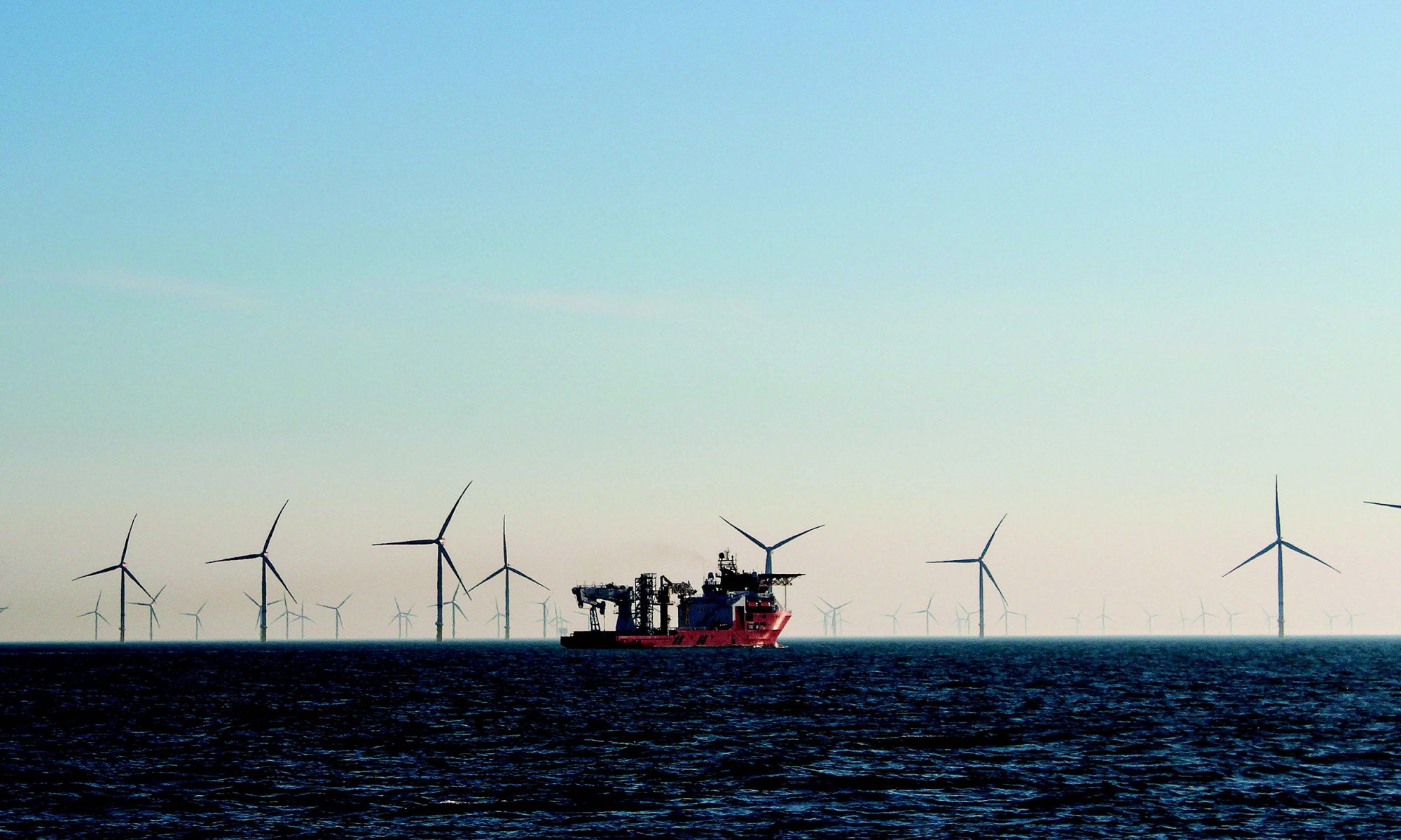Photo of a wind farm at sea and a ship to illustrate risk reduction