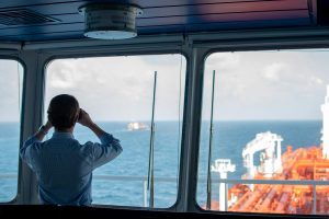 Ship captain looking out with binoculars to illustrate advancements in satellite connectivity technologies