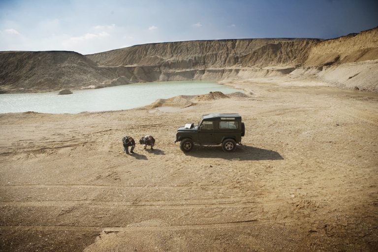 Exploradores en el desierto en camión arrodillados